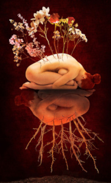 A woman showing her back, featuring a detailed tattoo design and flowers bloosoming from her hands
